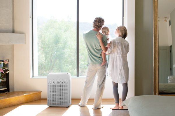 C545 Air Purifier on floor in bedroom next to two parents holding a baby