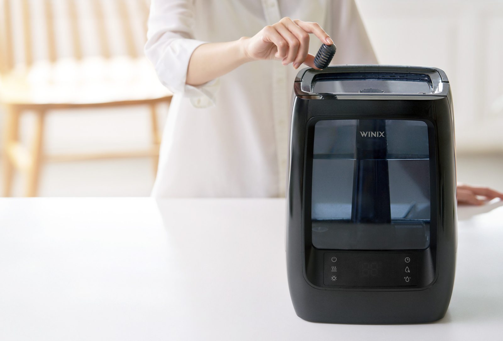 Hand inserting a demineralization capsule into the water tank of a L200 humidifier