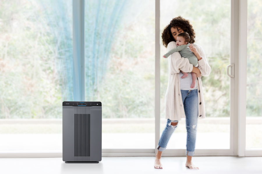 Mother holding a baby next to windows and 5300-2 air purifier
