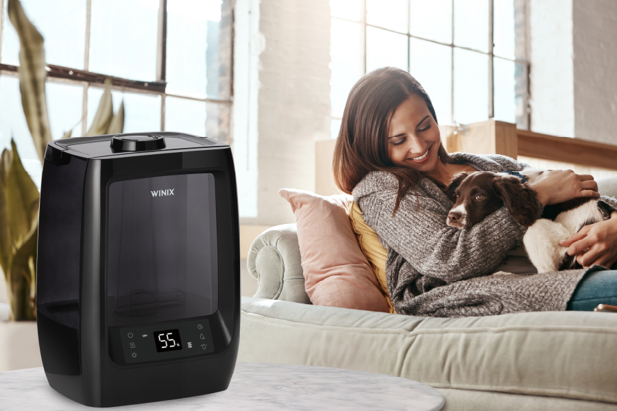 Woman sitting on couch with dog in her lap and Winix L200 humidifier on side table