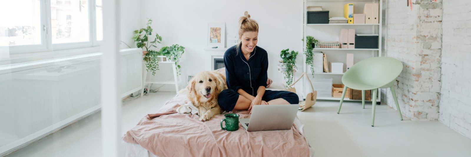 Woman and dog on bed with computer in bedroom